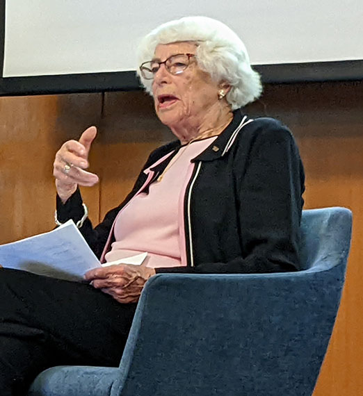 Woman sits holding a pencil. 