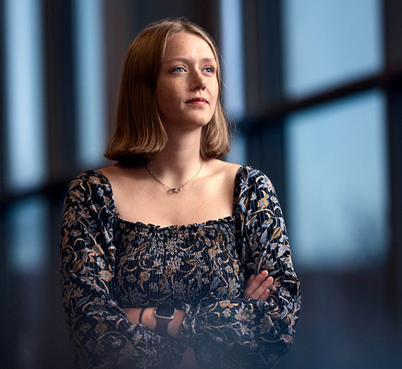 A woman stands next to several kayaks